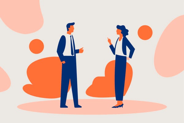 A man and woman in office attire discuss something against a gray and orange background.